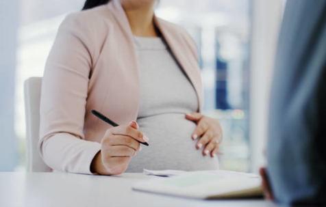 Pregnant woman signing paperwork