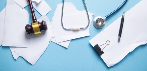 Judge gavel, stethoscope and torn documents.